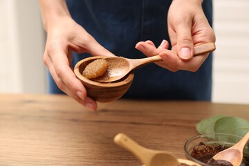Woman making natural body scrub at wooden table, closeup