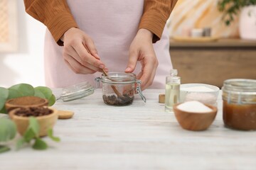 Woman making natural body scrub at white wooden table, closeup