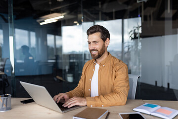 Smiling professional using laptop at modern office desk with bright surroundings