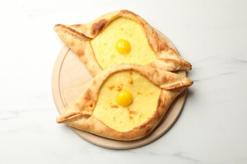 Tasty khachapuris with cheese and eggs on white marble table, top view