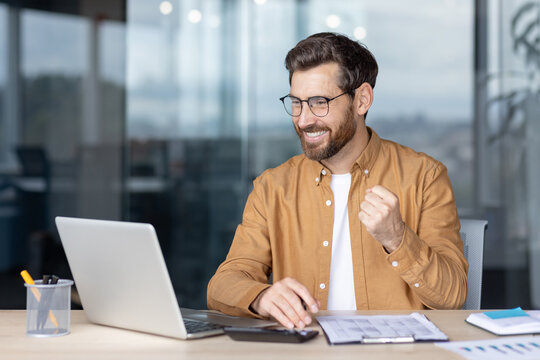 Happy professional celebrating success at work using a computer in modern office
