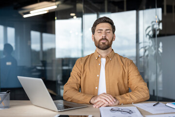 Fototapeta na wymiar Calm professional meditating at workplace in modern office setting