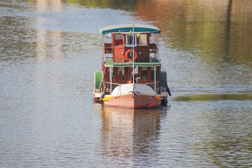 A pleasure boat floating on a river, reflected in the water © Sergey