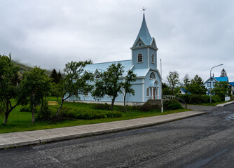 Famous Blue church surrounded by low clouds in Seydisfjordur in Iceland at the end of Rainbow Street