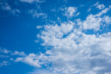 A photorealistic image of a blue sky with white clouds, showcasing a vast expanse of clear blue sky with scattered white clouds of various shapes and sizes. 