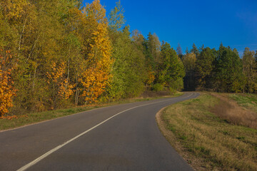 Autumn landscape and sunny evening, orange road and highway, asphalt and roadside.