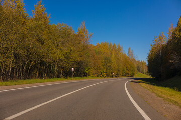 Fototapeta premium Autumn landscape and sunny evening, orange road and highway, asphalt and roadside.