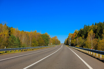 Autumn landscape and sunny evening, orange road and highway, asphalt and roadside.