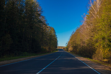 Fototapeta premium Autumn landscape and sunny evening, orange road and highway, asphalt and roadside.