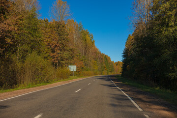 Autumn landscape and sunny evening, orange road and highway, asphalt and roadside.