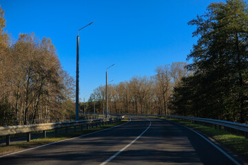 Autumn landscape and sunny evening, orange road and highway, asphalt and roadside.