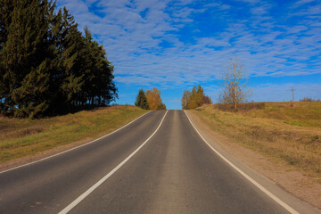 Fototapeta premium Autumn landscape and sunny evening, orange road and highway, asphalt and roadside.