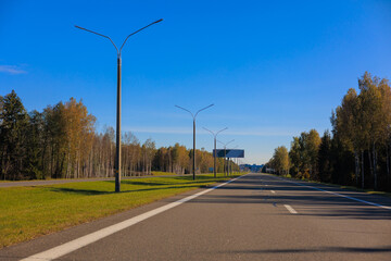 Fototapeta premium Autumn landscape and sunny evening, orange road and highway, asphalt and roadside.