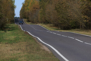 Autumn landscape and sunny evening, orange road and highway, asphalt and roadside.