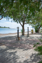 A serene beach scene with two black lamp posts with glass globes on top, positioned on the sandy...