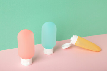 Travel bottles with body care cosmetics on colorful background
