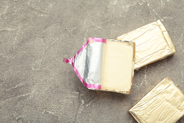 Processed cheese in foil on grey background