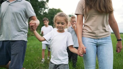 Family walking holding child hand outdoor in green park grass with parent and other child following together in summer nature setting showing bond happiness and lifestyle connection between generation - Powered by Adobe
