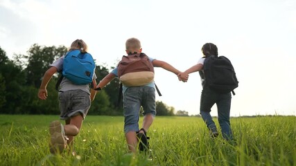 Running child holding hand with friend across green grass field under bright sky with backpack and school during summer outdoor adventure play near tree line and distant forest edge showing playful