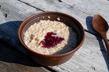 Breakfast in the open air in a picturesque place. Black coffee and oatmeal with raspberry jam in a clay pot with a view of the mountains. Picnic, breakfast in the mountains. Vegetarianism. Travel. 