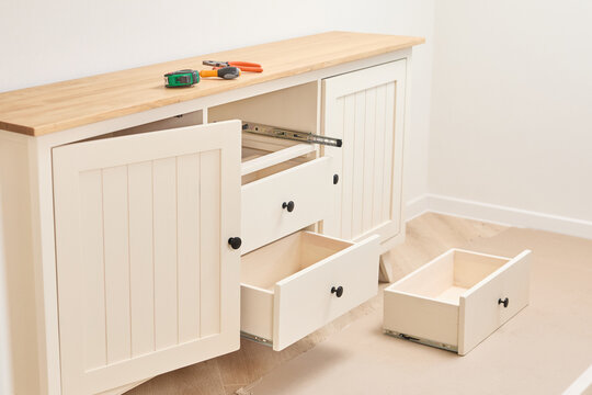 Skilled carpenter assembling wooden cabinet, using precision tools within well-lit, organized workshop setting - Powered by Adobe