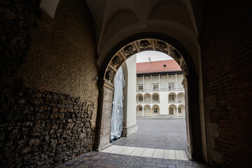Historic entryway to a courtyard in Krakow, Poland, with visitors exploring
