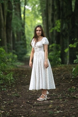 Portrait of a young beautiful dark-haired girl in a summer dress in the park in summer.