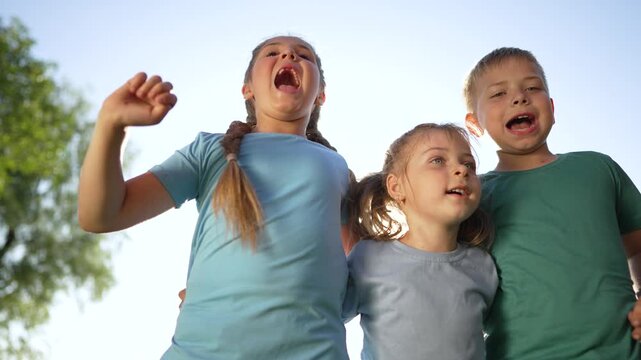 Children stand under bright sky smiling kid trio laugh play in sunlit park girl and boy close friend embrace summer smile carefree child energy happy outdoor activity playful bonding joyful