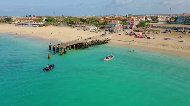 Cinematic drone footage of Santa Maria beach and pier, Sal Island, Cape Verde. Captured at golden hour with turquoise waters, fishing boats and tropical atmosphere in 4K and HD formats.
