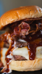 Massive gourmet burger with two juicy beef patties, overflowing melted cheese, crispy bacon, rich...