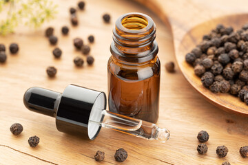 Black pepper essential oil on bottle on wooden table. Peppercorn oil Alternative medicine