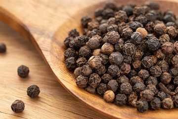Black pepper or pepercorn on wooden spoon. Cooking Spices. Piper nigrum