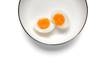 Minimal, bright food photograph showing two hard-boiled egg halves on a clean white plate. Plenty...