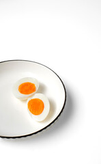 Portrait-oriented food image featuring two egg halves on a simple white plate with ample negative space for headlines or graphics—ideal for posters, stories, and menu designs.