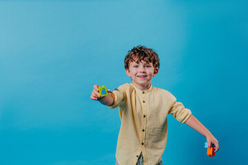 Little boy holding blocks with numbers standing over blue background