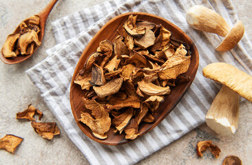 Dried mushrooms on wooden plate with fresh mushrooms and kitchen towel
