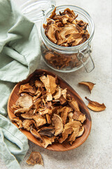 Dried mushrooms on wooden plate with fresh mushrooms and jar