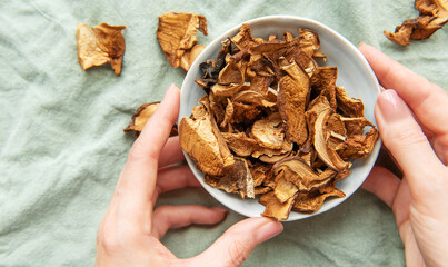 Chef holding bowl of dried mushrooms on green tablecloth
