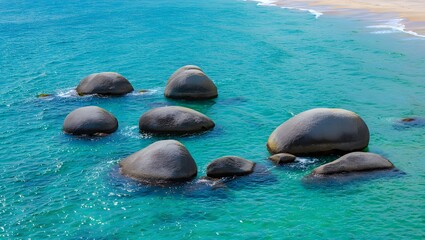 Photo of smooth round rocks emerge from the clear turquoise sea water