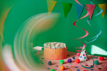 Birthday cake on the decorated table over green background with radial blur