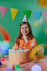 Happy little girl wearing party cap celebrating birthday
