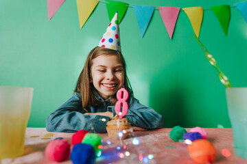 Happy smiling girl celebrating eight birthday sitting at a table