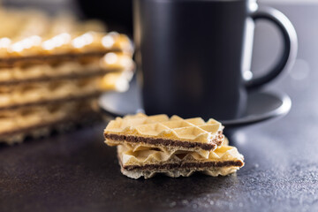 Sweet crispy wafers on black table.