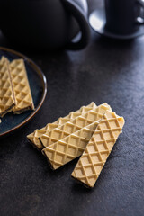 Sweet crispy wafers on black table.