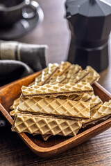 Sweet crispy wafers in bowl on wooden table.