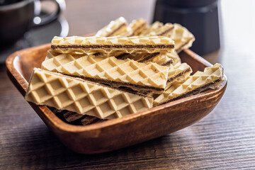 Sweet crispy wafers in bowl on wooden table.