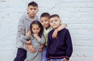 Four latin american children posing together in front of a white wall