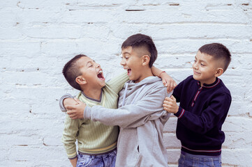 Three latin american boys laughing and hugging each other