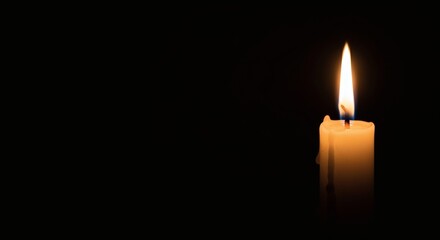 A glowing candle with soft light in the darkness for copy space object