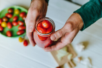 Hands of a person holding pickled cherry tomatoes